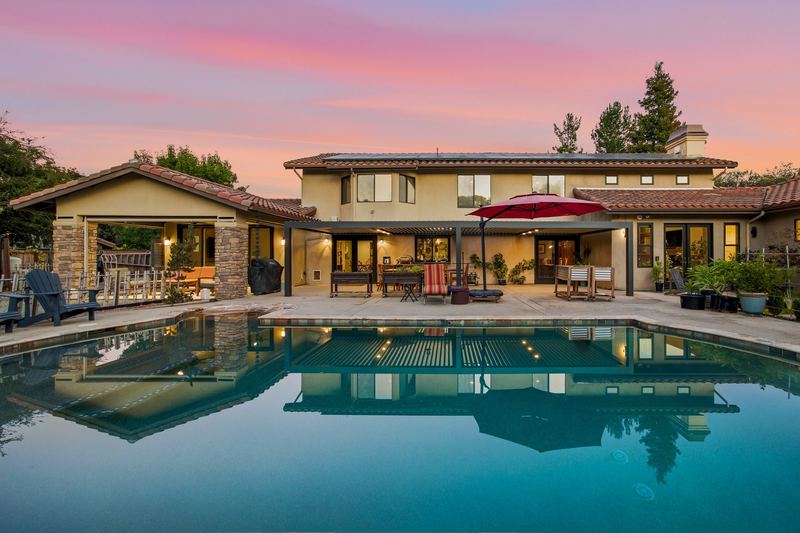 Backyard pool and rear elevation at dusk