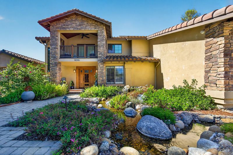 Stone and stucco front elevation with a rock lined stream